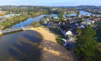 an aerial view of a small town by a river , with a sandy beach in the foreground at The Clan Terrigal