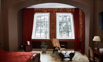 a room with a red brick wall and large windows , featuring two chairs and a table at Imperial
