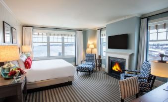 a cozy bedroom with a large bed , a fireplace , and a flat - screen tv . also a dining table in the room at Beauport Hotel Gloucester