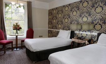 a hotel room with two beds , one on the left and one on the right side of the room at Risley Hall Hotel