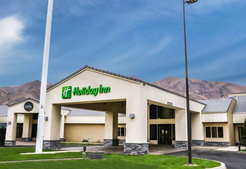 the exterior of a holiday inn with a large sign above the entrance and mountains in the background at Holiday Inn Clarkston - Lewiston