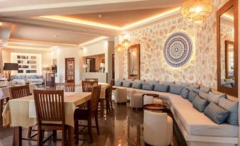 a large dining room with a couch , chairs , and a dining table surrounded by white chairs at Asteris Village