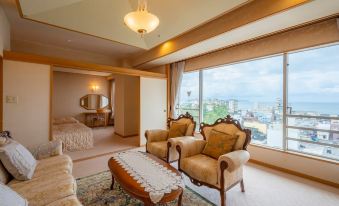 a luxurious living room with a large window and wooden furniture , including two chairs and a couch at Kaike Tsuruya