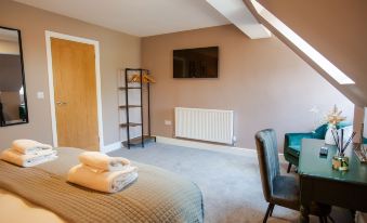 a cozy bedroom with a bed , towels , and a tv on the wall , as well as a chair and a wooden door at Woodfalls Inn