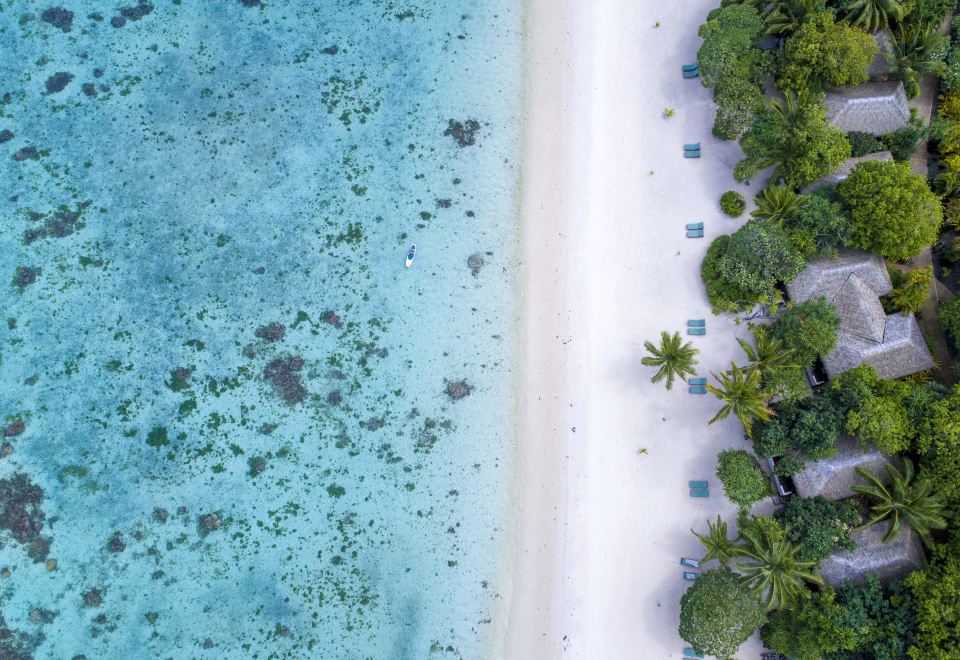 a bird 's eye view of a tropical beach with clear blue water and lush green vegetation at Small Luxury Hotels of the World - Pacific Resort Aitutaki