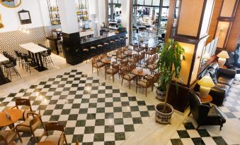 a large dining area with wooden chairs and tables , black and white checkered floor , and a bar at THB Felip - Adults Only