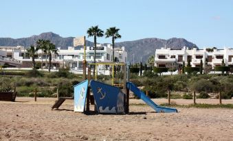 a blue and white pirate ship playground on the beach , with palm trees in the background at Casa Blanca