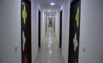 a long , well - lit hallway with white walls and black doors decorated with colorful designs , leading to an exit at the end at Hotel President