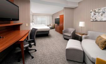 a modern hotel room with a large bed , desk , chairs , and a flat - screen tv at Courtyard Lufkin