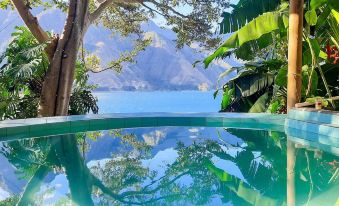 a large swimming pool surrounded by lush greenery , with a view of a mountain in the background at Eco Hotel Uxlabil Atitlan