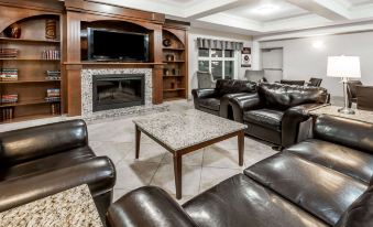 a spacious living room with dark brown leather furniture , a marble coffee table , and a large screen tv at Ramada by Wyndham High River