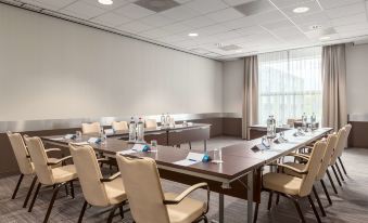 a conference room with a long table and chairs arranged in a semicircle , providing seating for a group of people at NH Amsterdam Schiphol Airport