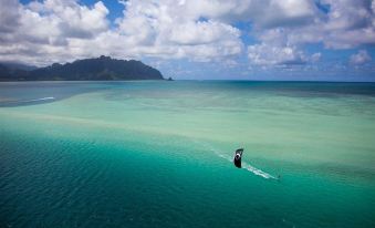 a man is kiteboarding on a calm body of water , with a mountain in the background at Paradise Bay Resort