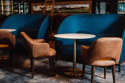 a blue chair and a table are in front of a wall with a painting at Oval Hotel at Adelaide Oval, an EVT hotel
