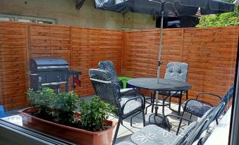 a small outdoor patio with a grill , dining table , chairs , and potted plants , all under a wooden fence at Bike Apartment