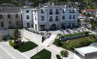 aerial view of a large white building with a courtyard , surrounded by greenery and stairs leading up to it at Hotel Fantasy