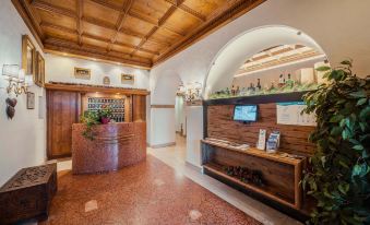 a hotel lobby with a reception desk and a tv mounted on the wall , surrounded by various items and decorations at Royal Hotel Cortina