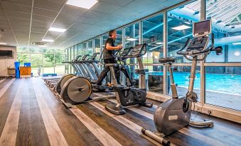 a man is working out in a gym , using various exercise equipment and machines near a pool at Dunkeld House Hotel