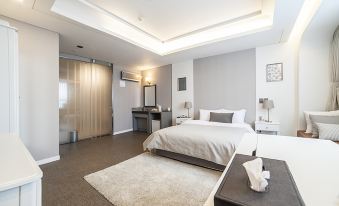 a modern bedroom with a large bed , gray carpet , and white bedding , accompanied by a desk and mirror at Polaris Hotel