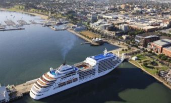 a large cruise ship docked at a port with a city skyline in the background at Admiralty Inn