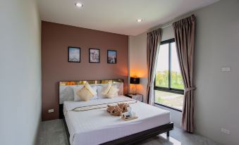 a well - lit bedroom with a white bed , curtains , and a view of the outdoors through a large window at The Living Hotel SamutPrakan