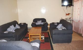 a living room with black couches and chairs arranged in a line , along with a television mounted on the wall at The Ree