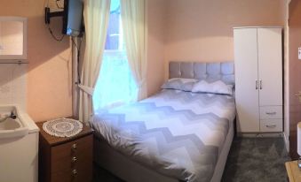 a neatly made bed with white and gray zigzag patterned bedding is situated in a room with a window at Gracelands Guest House