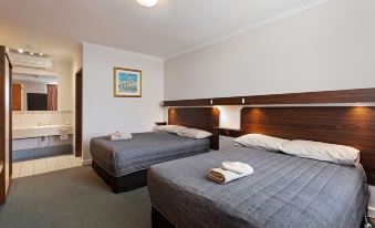 a hotel room with two beds , one on the left and one on the right side of the room at Maffra Motor Inn