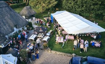 an aerial view of a large group of people gathered in a field , with tents and tables set up for an event at The Hatchet Inn