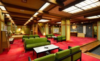 a large , well - lit room with red carpeting and multiple couches arranged in a seating area at Osakaya Ryokan