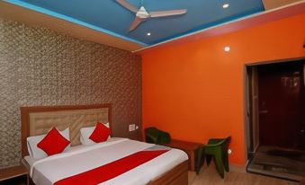 a hotel room with a large bed , orange walls , and a green desk , along with a fan on the ceiling at Collection O 27949 Hotel Kriti Green