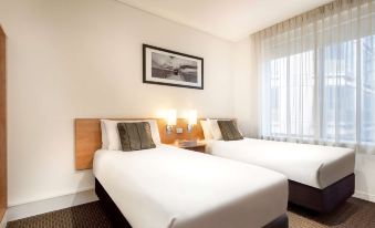 a hotel room with two beds , a window , and a framed picture on the wall at Ibis Melbourne Hotel and Apartments