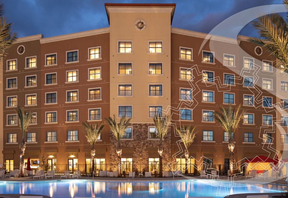 an exterior view of a hotel with a large swimming pool in the foreground , surrounded by palm trees at Soboba Casino Resort