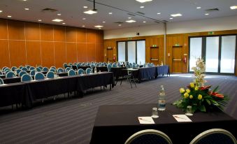 a conference room set up for a meeting , with tables and chairs arranged in rows at VIP Executive Santa Iria Hotel