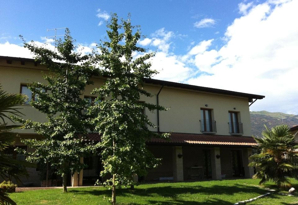 a large house with a green lawn and trees in front of it , under a blue sky with white clouds at Ca' Del Bosco
