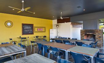 a dining area with multiple tables and chairs , as well as a brick oven in the background at Myrtleford Motel on Alpine