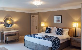 a large bed with a blue and white patterned blanket is in the center of a room with a chandelier at The Woburn