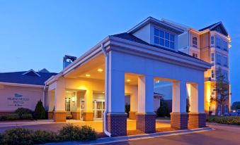 a large hotel building with a covered entrance and columns , illuminated at night against a blue sky at Homewood Suites by Hilton Minneapolis-New Brighton