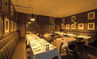 a well - lit dining room with tables and chairs arranged for a group of people to enjoy a meal together at The Station Hotel