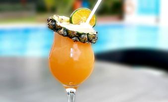 a glass of orange juice is sitting on a table next to a swimming pool at Forbis Hotel