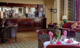 a dining room with a wooden bar , red chairs , and a table set for two at The Midland Hotel