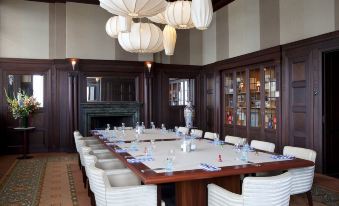 a large dining table surrounded by white chairs in a room with a fireplace and lanterns at Hotel New York