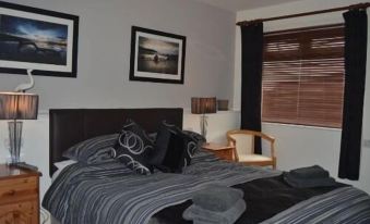 a bedroom with a large bed , striped sheets , and framed pictures on the wall at The Elmer