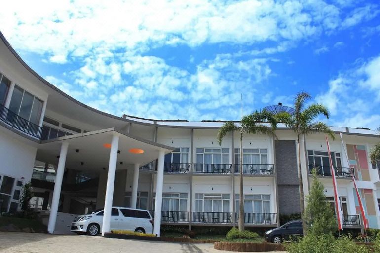 a white building with multiple balconies and a car parked in front of it , under a blue sky with clouds at Seulawah Grand View