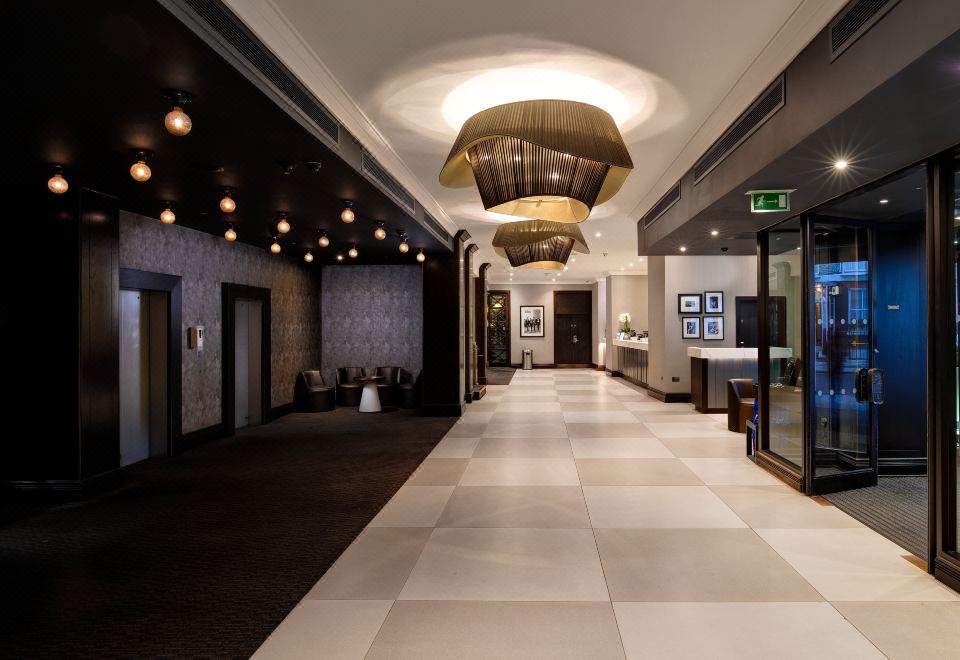 a modern , well - lit hallway with white tiles and black and white checkered flooring , featuring hanging lights and gold accents at President Hotel