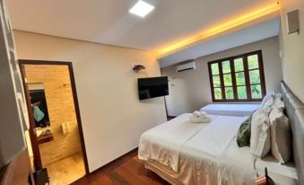 a hotel room with a large bed , wooden floors , and a television mounted on the wall at Pousada Simpatia da Ilha