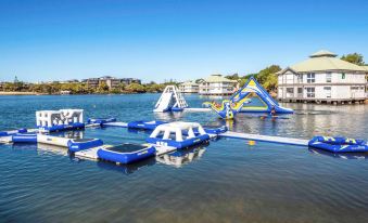 a blue and white inflatable obstacle course floating on a body of water near a house at Novotel Sunshine Coast Resort