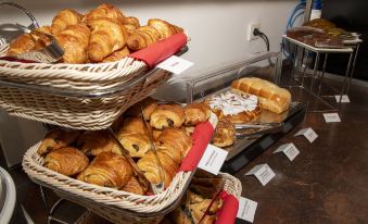 a display of fresh baked pastries , including croissants and bread , on a counter with labels at K Hotel