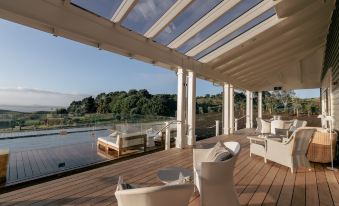 a modern outdoor living space with a wooden deck , white furniture , and a panoramic view of the outdoors at Rosewood Kauri Cliffs