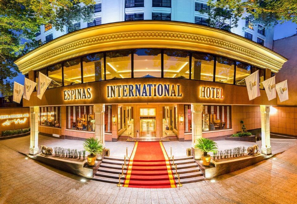 An urban hotel with a front entrance illuminated at dusk or night time at Espinas International Hotel